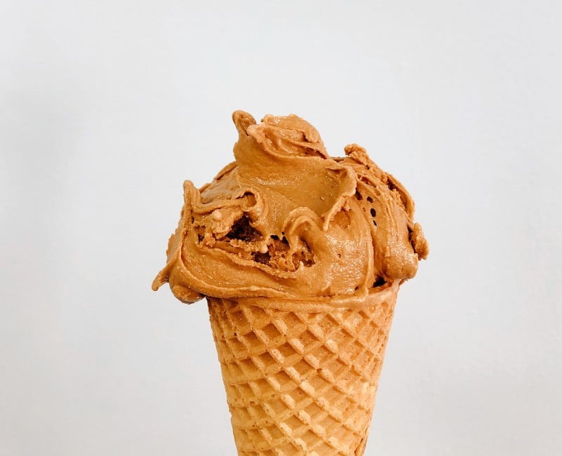 Ice Cream Overrun Image. Carmel colored ice cream in a waffle cone.