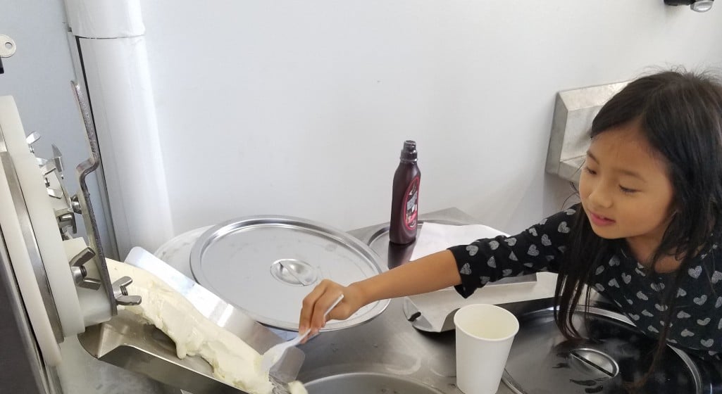 Choosing frozen custard equipment decisions. One decision is are customers going to serve themselves? This image shows an Asian girl spooning out frozen custard with a spoon.