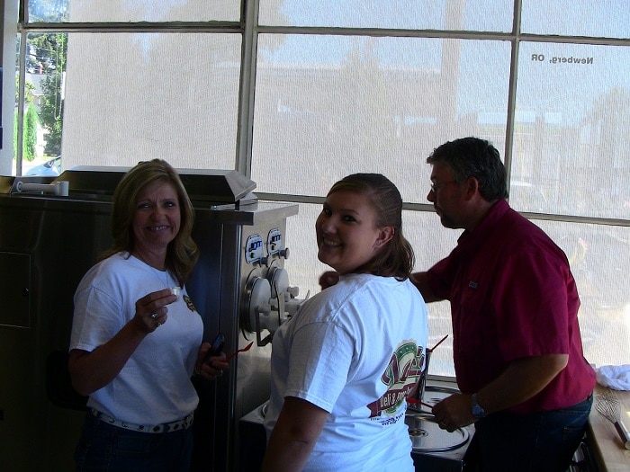 Gravity Fed Frozen Custard Machines Image: It's a man dressed in a red shirt training two women on how to operate a two barrel frozen custard machine. The women are wearing white t-shirts with the company logo, etc.