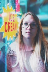 Maintaining frozen custard machines image. Young woman standing outside ice cream shop. She isn't smiling.