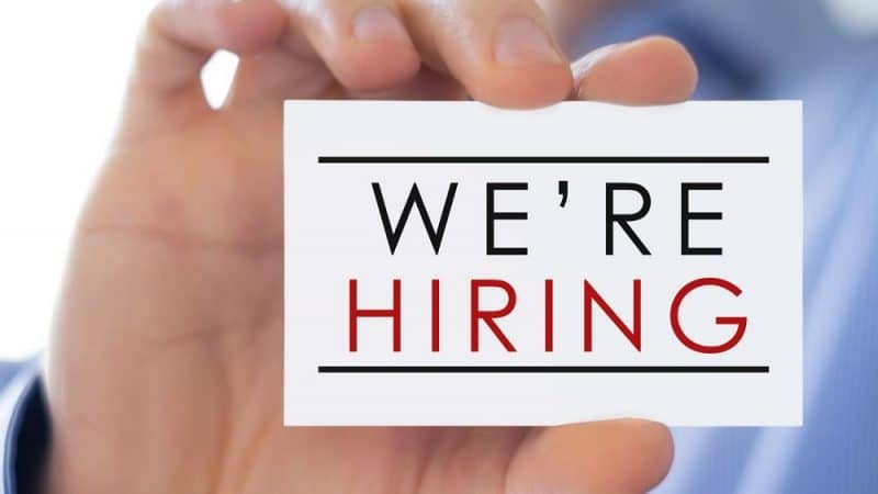 Ice cream shop staffing solutions image closeup of man's hand holding a sign "WE"RE HIRING"