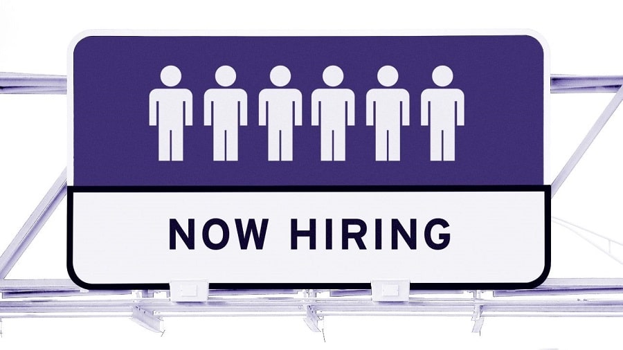 Ice cream shop staffing solutions image sign with six white icons of a person with purple background. Underneath are the words in black text "NOW HIRING" with white background.