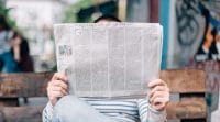 From the desk of Tony Carey image shows man sitting on bench holding an opened newspaper.